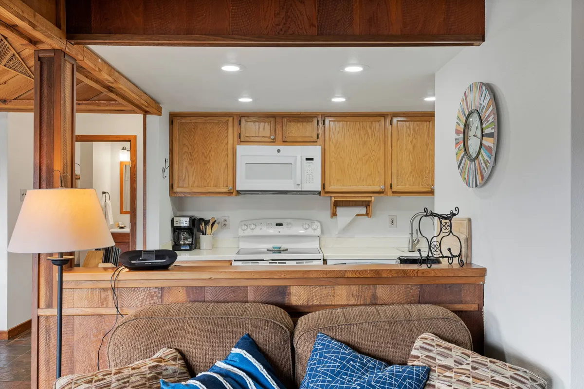 A welcoming kitchen area adjacent to a cozy couch and a large wall clock, ideal for both meal preparation and relaxing. The space is functional, bright, and designed for comfort, making it easy to unwind after a day outdoors.