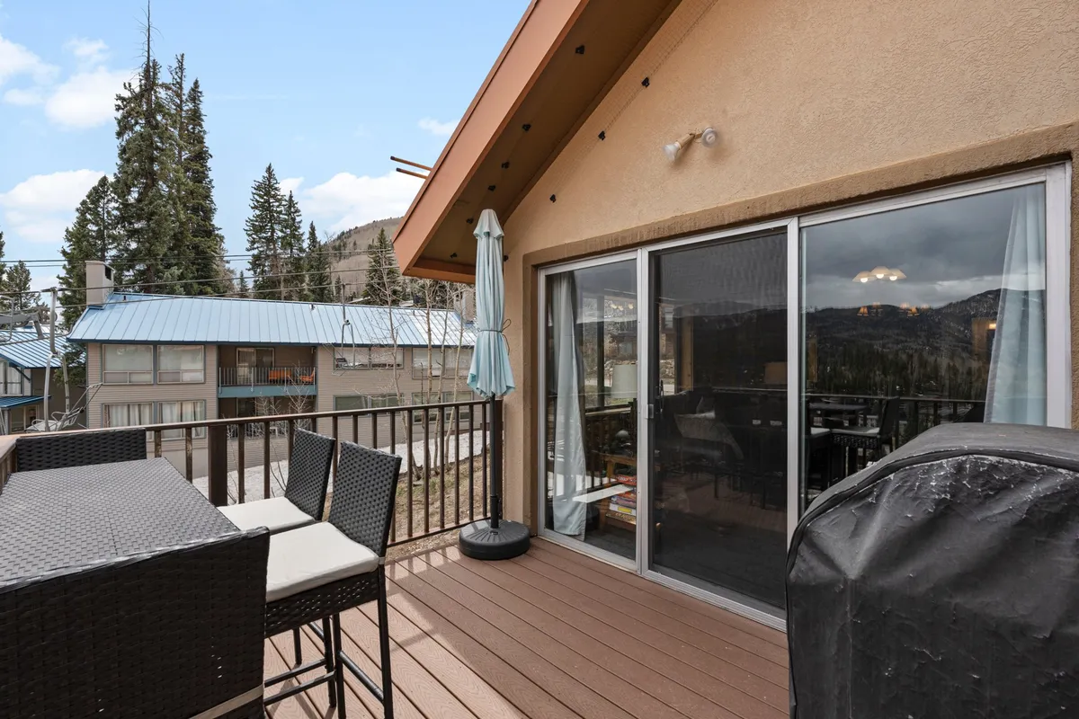 An inviting exterior shot of an outdoor dining set with an umbrella, overlooking a panoramic mountain view. The scene is tranquil, perfect for family meals, socializing, or simply soaking in the fresh mountain air.